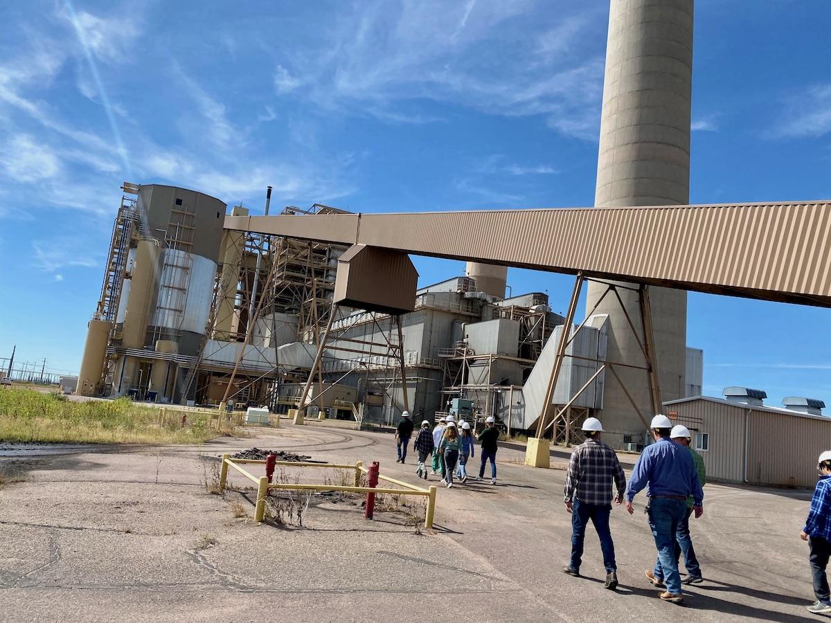 人 walking around an industrial structure wearing hard hats